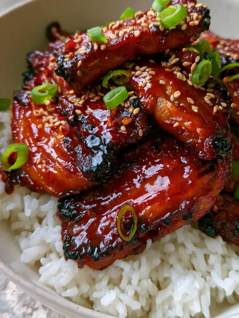 Extreme close-up of meaty oyster mushrooms drenched in a thick crimson gochujang glaze with visible charred edges. (Gochujang Mushrooms)
